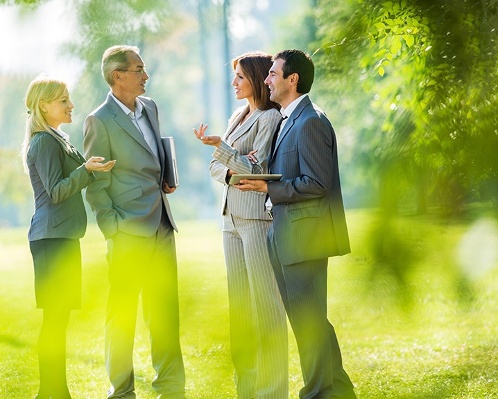 People in suits talking to each other outdoors.