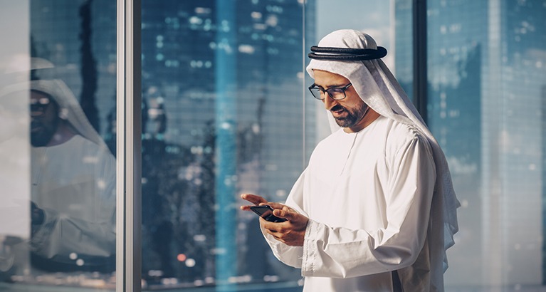 Muslim businessman looking at his phone.