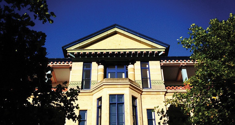 Cambridge Judge Business School in front of a bright blue summer sky.