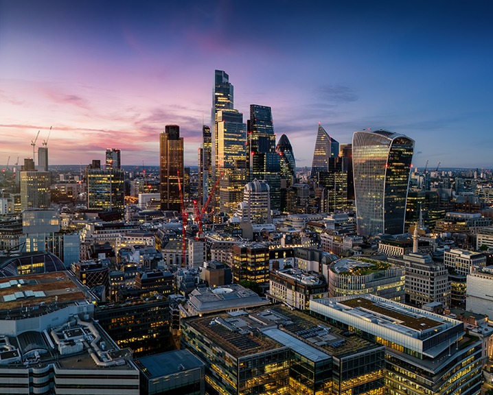 Aerial view of the illuminated skyscrapers at the City of London, England, during evening time with a colourful sky.