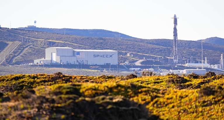 SpaceX Falcon rocket standing on launch pad preparing for liftoff at California aerospace facility.