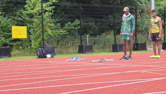 Jason Sewanyana and athlete Jaco Smit on the training track at the Commonwealth Games.