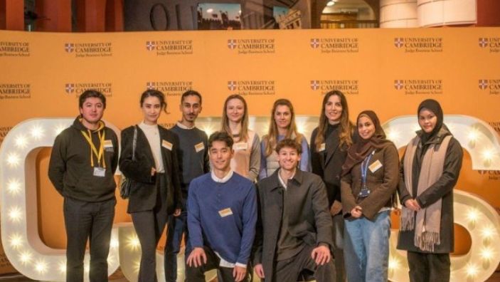 Students at EnterpriseTECH posing in front of the Cambridge Judge banner and logo.