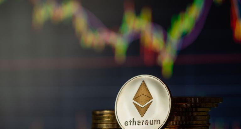 Ethereum logo in front of coins and a chart.