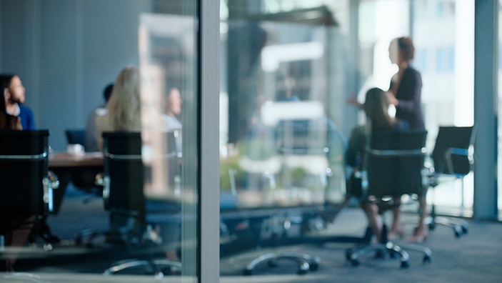 Boardroom presentation behind a glass wall.