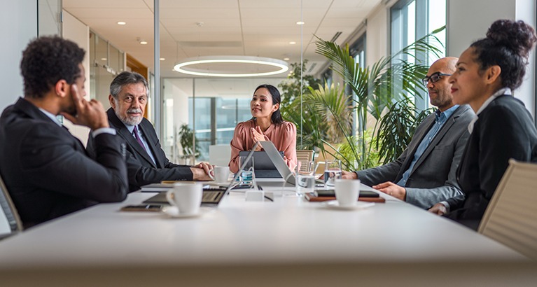 Group of male and female executives sitting at conference table in modern office and exchanging ideas.