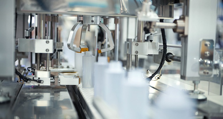 Manufacturing production line with automated dispenser for small plastic bottles.
