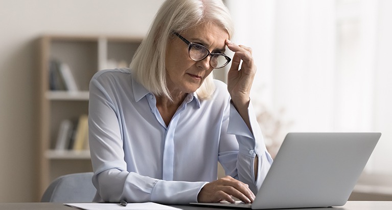Women looking at her laptop with uncertainty.